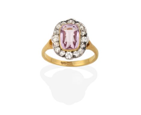 A Pink Tourmaline and Diamond Cluster Ring, the cushion cut pink tourmaline in a yellow rubbed over setting within a border o