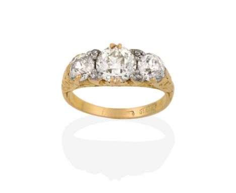 A Diamond Three Stone Ring, the graduated old cut diamonds with eight-cut diamond accents, in a yellow scroll carved claw set