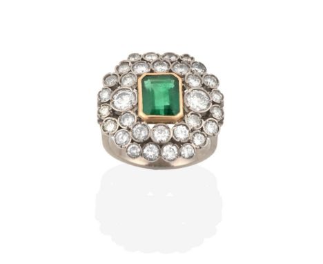 An Emerald and Diamond Ring, the emerald-cut emerald in a yellow rubbed over setting, within a double border of vari-sized ro