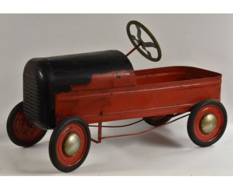 A vintage early 1950s Tri-ang Duke peddle car, red and black painted metal body, full width front grill, solid wheels, rubber