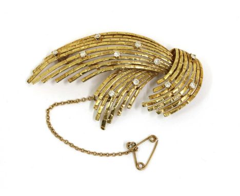 A Continental gold diamond set spray brooch, c.1970, with scattered brilliant cut diamonds claw set to the textured spray, to