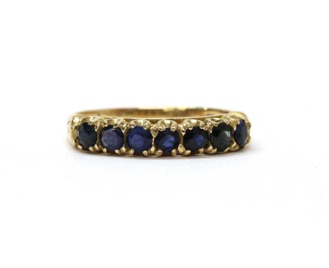 A 9ct gold sapphire set half eternity ring, with a row of seven round mixed cut sapphires, claw set, to a plain shank, London