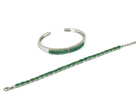 A silver emerald set bracelet, with a row of oval mixed cut emeralds, approximately 6 x 4mm, claw set to articulated collets,