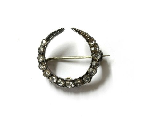 A silver and gold, diamond crescent brooch, with a row of graduated rose cut diamonds in a silver cut down collets, backed in