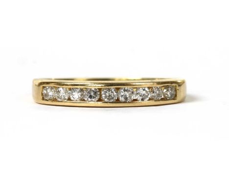 A gold diamond half eternity ring, with a row of brilliant cut diamonds, channel set, to a plain shank, tested as approximate