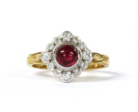 An 18ct gold ruby and diamond off set square cluster ring, with a round cabochon ruby, approximately 5mm, rub set, to surroun