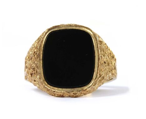 A 9ct gold onyx signet ring, with a cushion shaped onyx tablet and textured mount, Birmingham 1971, 6.15g.Finger size U