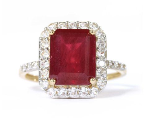 A 9ct gold fracture filled ruby and zircon halo cluster ring, with an emerald cut fracture filled ruby, approximately 10 x 8m