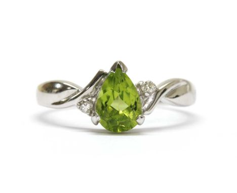 A white gold peridot and diamond ring, with a pear mixed cut peridot, claw set, with a brilliant cut diamond at each side, to