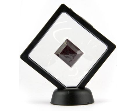 A large cushion cut ruby in a perspex stand, 2.5 x 3 x 1cm.