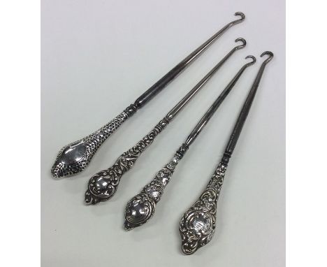 A group of four silver button hooks with embossed handles. Various dates and makers. Approx. 114 grams. Est. £30 - £40.