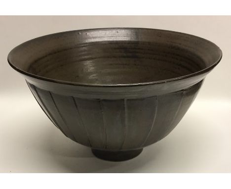 DAVID LEACH: (British: 1911 - 2005): A dark brown glazed stoneware pottery bowl with fluted sides on pedestal foot. Impressed