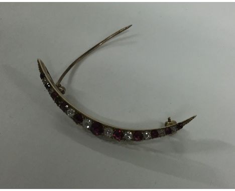 A ruby and diamond crescent brooch in gold mount. Approx. 3.4 grams. Est. £100 - £150.
