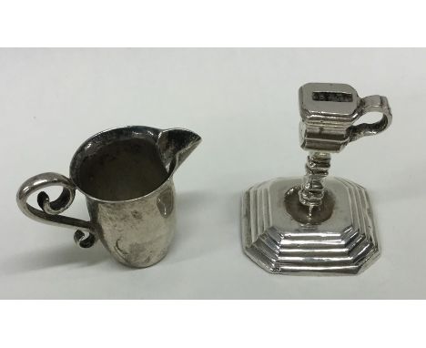 An unusual Antique miniature silver jug together with a silver chamber stick. Approx. 22 grams. Est. £40 - £60.