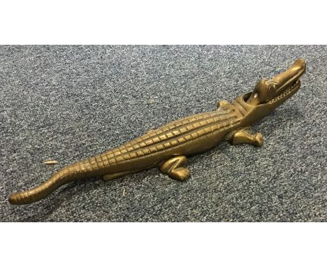 A long brass nutcracker in the form of an alligator. Est. £15 - £20.