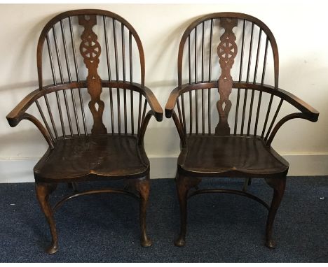 A pair of oak Windsor chairs on curved stretcher bases with stick back. Est. £60 - £80.