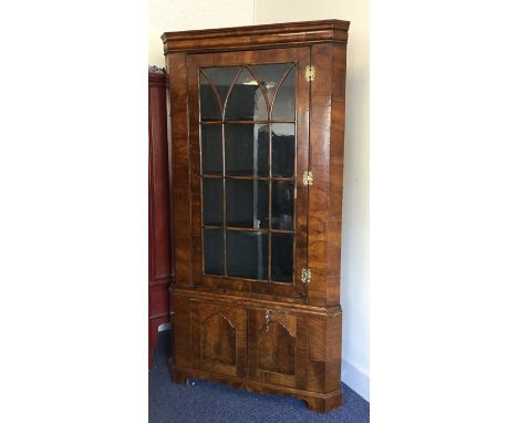 A large walnut veneered Antique corner cupboard with bevelled glass to bracket feet. Est. £100 - £200.