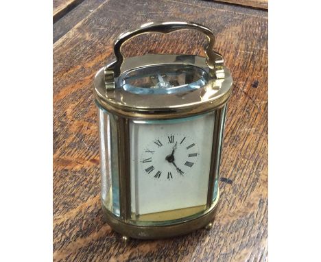 An oval brass mounted carriage clock with glass sides. Est. £40 - £60.