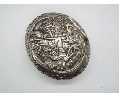A continental white metal snuff box of oval form, stamped 800, the hinged lid with repousse decoration of St George slaying t