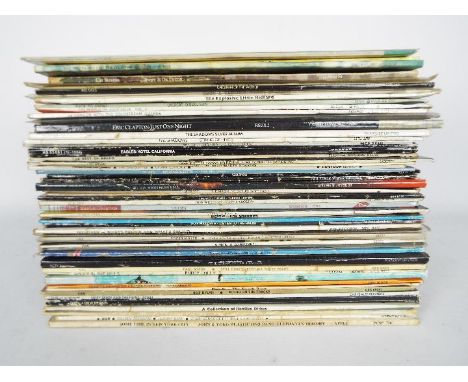 A quantity of 12" vinyl records to include Elton John, George Harrison, The Beatles, Beach Boys, Bob Dylan, Queen and similar