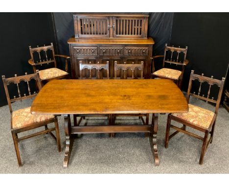 An Ercol dark elm dining room suite, comprising trestle dining table, four chairs, two carver chairs, sideboard and wall moun