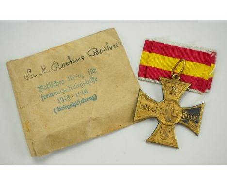 Baden: Kreuz für freiwillige Kriegshilfe, in Tüte.Kriegsmetall vergoldet, mit Band, in Verleihungstüte, bedruckt, mit Trägern