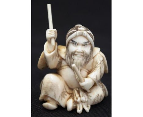 Japanese carved ivory okimono seated man with batons, signed to base, (height 5cm approx). NOTE: Export of this item is not p