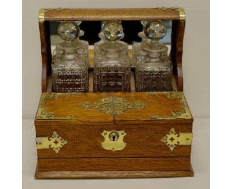 Edwardian English oak three decanter tantalus with brass fittings,