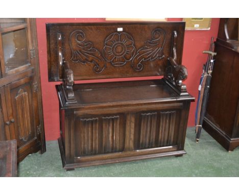 An oak Monk's bench, lion shaped arms, linen fold panelling to front 
