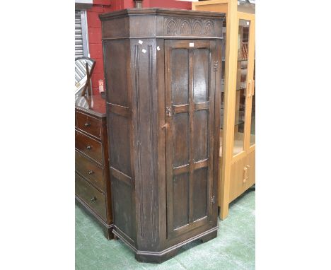 A Priory style dark oak hall robe, lunette carved frieze, canted angles, panelled door, bracket feet. 179cm high x 86cm wide 