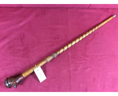 A short walking stick of thistle and twist form with carved humorous head handle