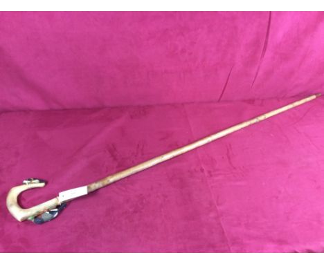 A walking stick with horn handle and woodpecker decoration
