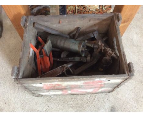 An old crate containing various grease guns, foot pump, and other old tools