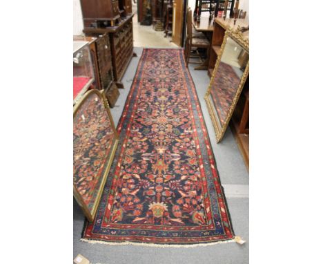 A Persian runner, or hall carpet, dark blue ground with stylized floral decoration.