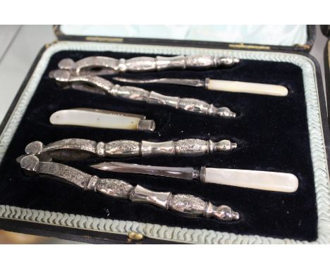 A cased after dinner set comprising nutcrackers with picks and a silver and mother-of-pearl fruit knife, cased.