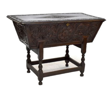 A 19th century carved oak lidded dough trough, the hinged cover with central diamond carving surrounded by scrolling foliate,