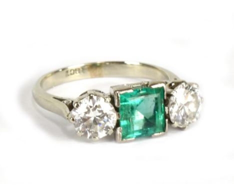 An 18ct white gold emerald and diamond ring, the central square cut emerald weighing approx 1ct flanked by twin 0.5ct rounded