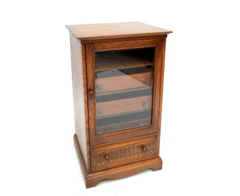 ERCOL; a 'Golden Dawn' music cabinet with glazed door enclosing three shelves and with drawer to base, width 56cm.