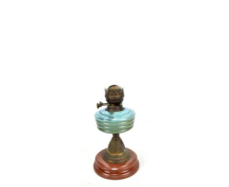 An oil lamp with ribbed blue glass reservoir and clear glass chimney on ceramic base, height 57cm.
