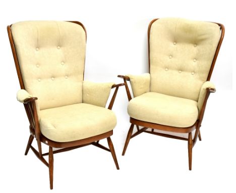 ERCOL; a pair of 'Golden Dawn' armchairs with padded back, seat and arms, and outswept legs.