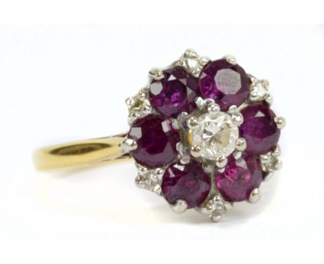 A diamond and ruby daisy ring, the central raised stone surrounded by six rubies and diamond chips, size L, approx 3.7g, in h