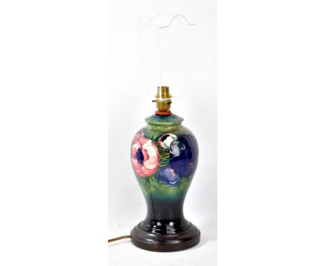 MOORCROFT; a tube line decorated 'Anemone' patter baluster lamp base on green ground and wooden stand, height including base 