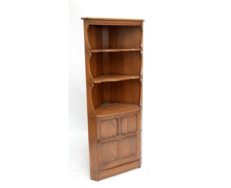 ERCOL; a 'Golden Dawn' freestanding corner cupboard with two shelves to the upper section and panelled cupboard beneath, widt