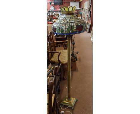 A brass standard lamp with Tiffany style leaded shade.