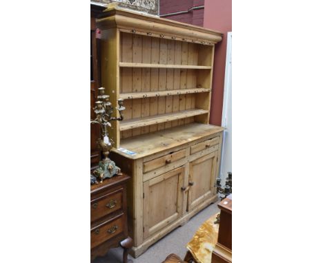 A 19th century pine dresser, the boarded plate rack above a base with two drawers and two cupboard doors and raised on bracke
