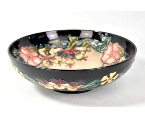 MOORCROFT; a floral tubeline decorated footed bowl on navy ground, impressed marks and year cipher for 1997 to base, diameter