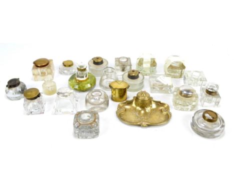 Twenty clear glass inkwells of varied form, numerous with brass or base metal tops, and a brass Art Nouveau style ink stand w