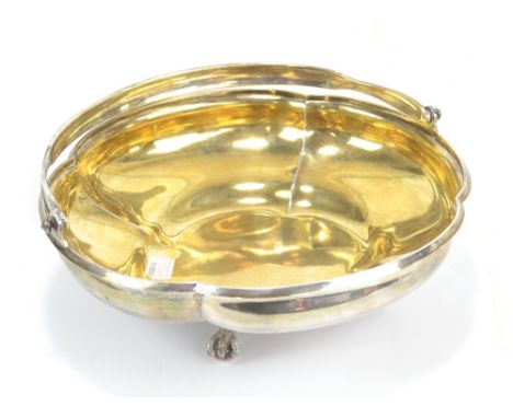 PAVEL SAZIKOV; a Russian 84 zolotnik grade silver lobed bowl with swing handle and gilt interior on four claw and ball feet, 