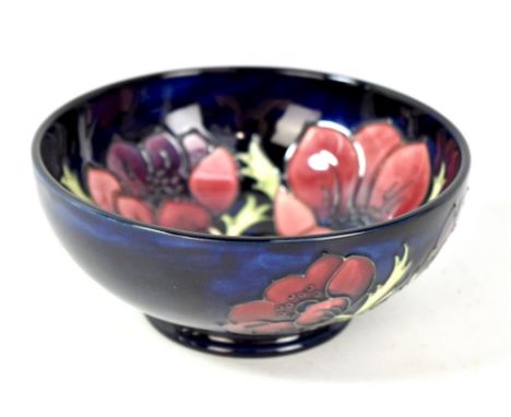 MOORCROFT; a floral tube line decorated footed bowl on navy ground, WM monogram and impressed marks to base, diameter 16.2cm 