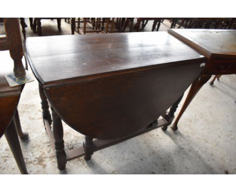 A 20th century reproduction oak gate leg table of traditional design. 74 CCM. X106CM. Sold with a reproduction mahogany bow f